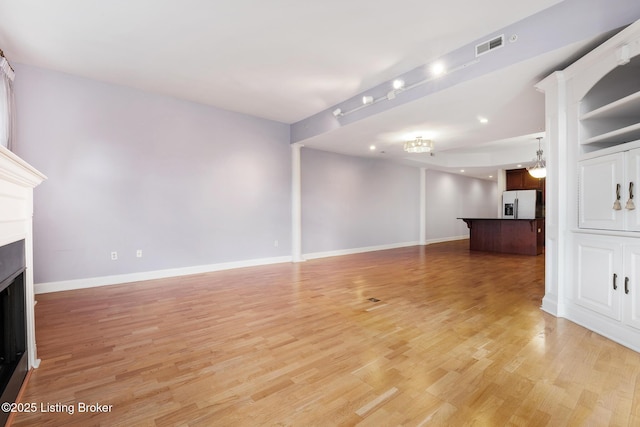 unfurnished living room featuring baseboards, a fireplace, and light wood finished floors