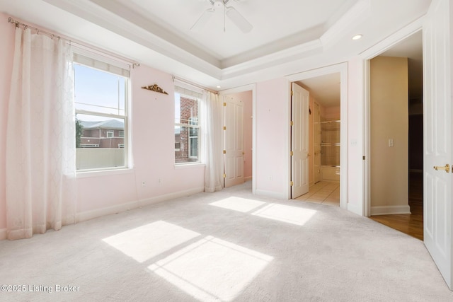 unfurnished bedroom with carpet floors, a tray ceiling, and baseboards