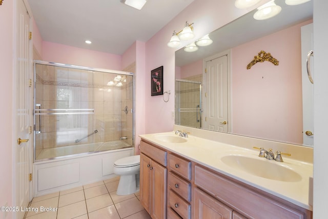 bathroom featuring double vanity, bath / shower combo with glass door, a sink, and tile patterned floors