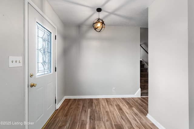 entryway featuring baseboards, stairway, and wood finished floors