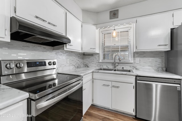 kitchen featuring tasteful backsplash, stainless steel appliances, under cabinet range hood, white cabinetry, and a sink