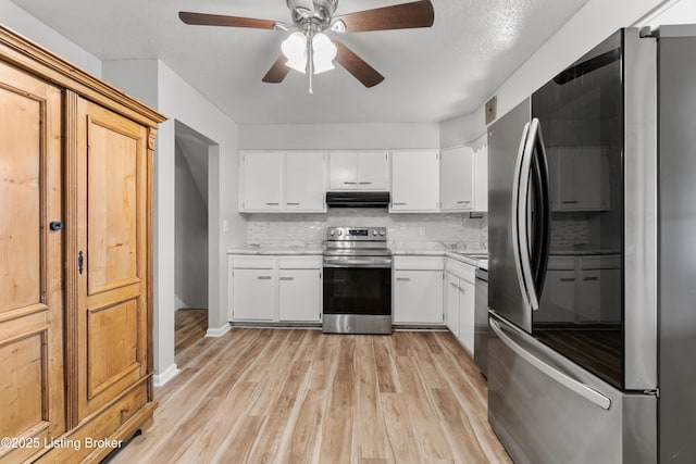 kitchen with under cabinet range hood, stainless steel appliances, light wood-style floors, light countertops, and backsplash