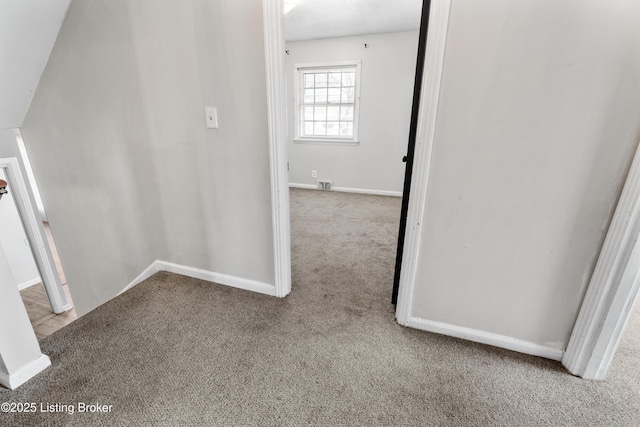 corridor with baseboards, visible vents, and carpet flooring