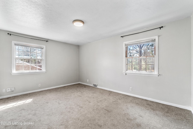 spare room featuring a textured ceiling, carpet flooring, and visible vents