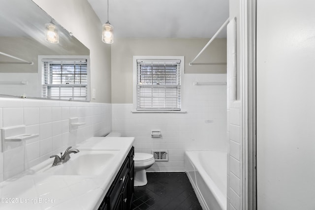 full bath with a wainscoted wall, tile walls, toilet, vanity, and tile patterned flooring