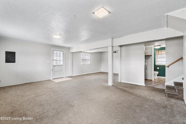 below grade area featuring stairs, carpet floors, a textured ceiling, and electric panel