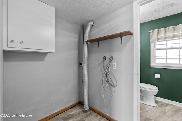 bathroom featuring baseboards, a textured ceiling, toilet, and wood finished floors