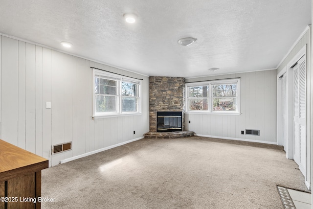 unfurnished living room featuring carpet floors, a fireplace, visible vents, and a wealth of natural light