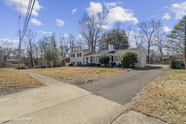 view of front of home featuring a chimney, a front lawn, and aphalt driveway