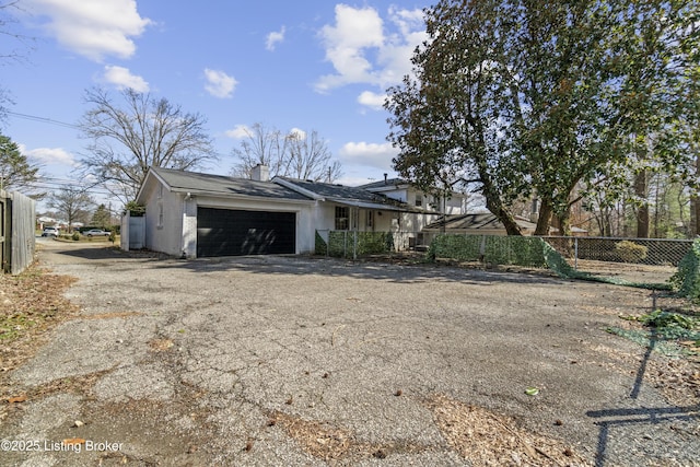 view of front of property featuring an attached garage, brick siding, fence, driveway, and a chimney