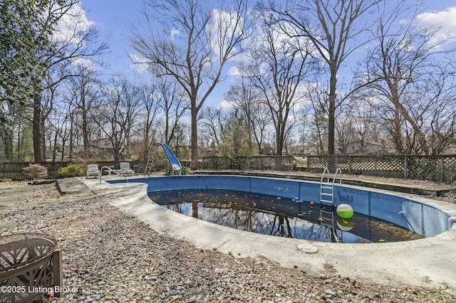 view of swimming pool featuring an empty pool, a water slide, and a fenced backyard