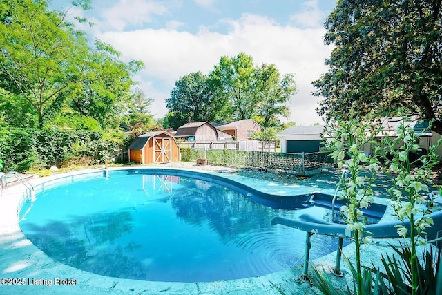 view of pool featuring a fenced backyard, an outdoor structure, and a storage shed