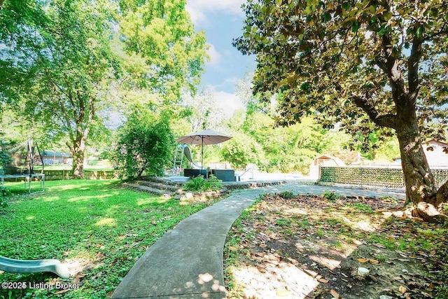 surrounding community featuring a trampoline, fence, and a lawn