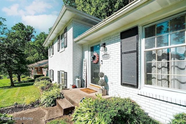 view of side of property with brick siding and a lawn