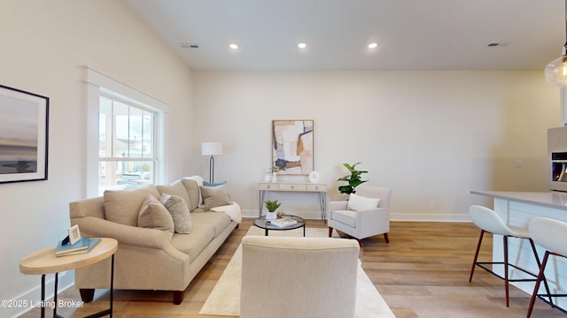 living area with light wood finished floors, baseboards, visible vents, and recessed lighting