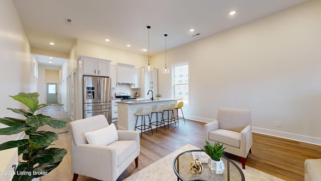 living area featuring light wood-type flooring, baseboards, and recessed lighting