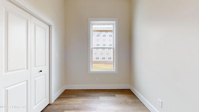 spare room with baseboards and light wood finished floors