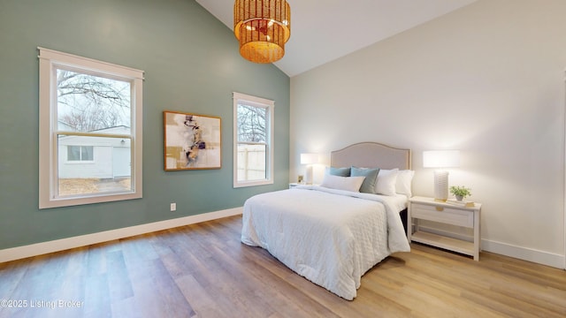 bedroom featuring high vaulted ceiling, light wood-style flooring, and baseboards