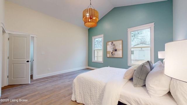 bedroom with vaulted ceiling, baseboards, and wood finished floors