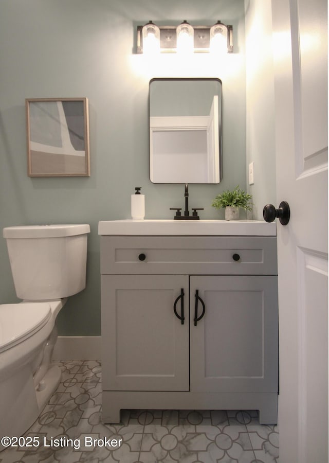 half bathroom featuring toilet, vanity, and baseboards