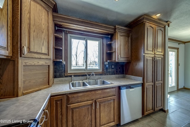 kitchen featuring open shelves, tasteful backsplash, light countertops, stainless steel dishwasher, and a sink