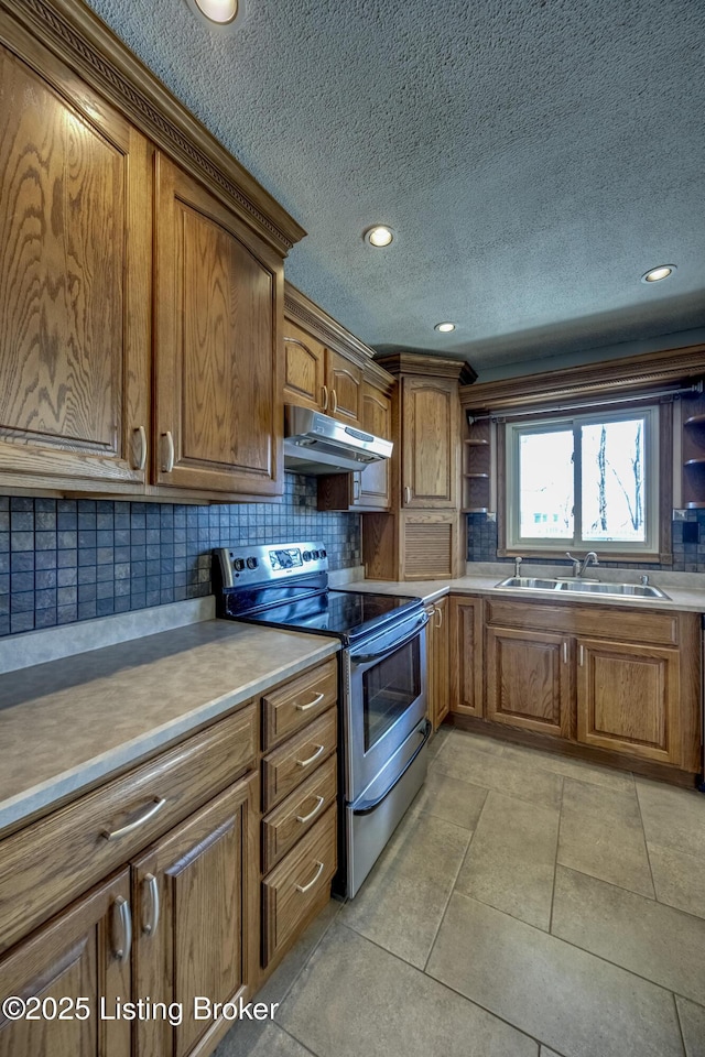 kitchen featuring stainless steel range with electric stovetop, under cabinet range hood, brown cabinets, and a sink