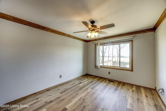 empty room with light wood-style flooring, visible vents, ceiling fan, and crown molding