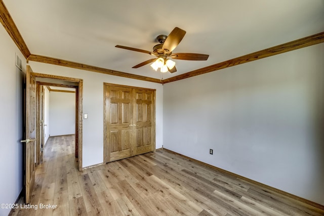 unfurnished bedroom featuring light wood-type flooring, a closet, and crown molding