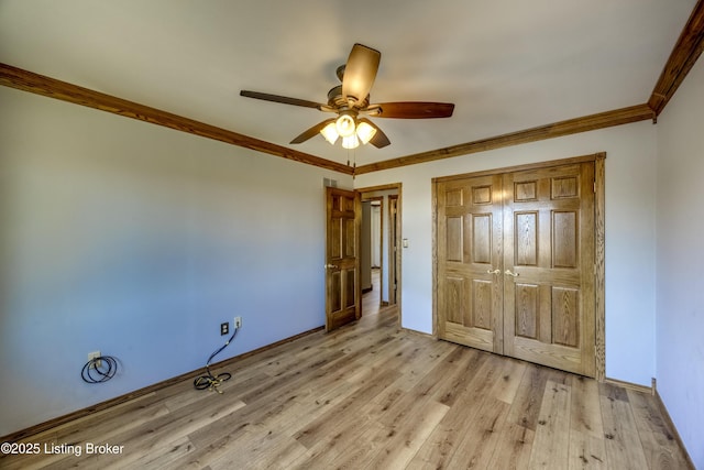 unfurnished bedroom with crown molding, light wood finished floors, a closet, ceiling fan, and baseboards