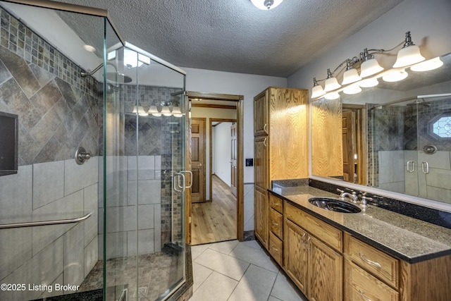 full bath featuring a textured ceiling, a stall shower, tile patterned flooring, and vanity