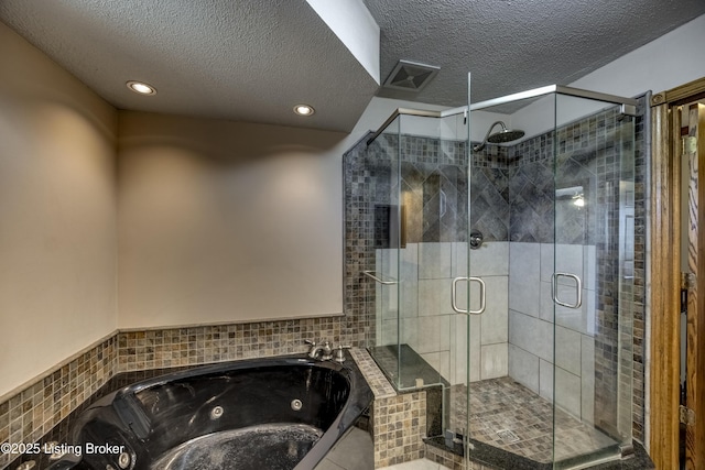 full bathroom featuring a jetted tub, a stall shower, visible vents, and a textured ceiling