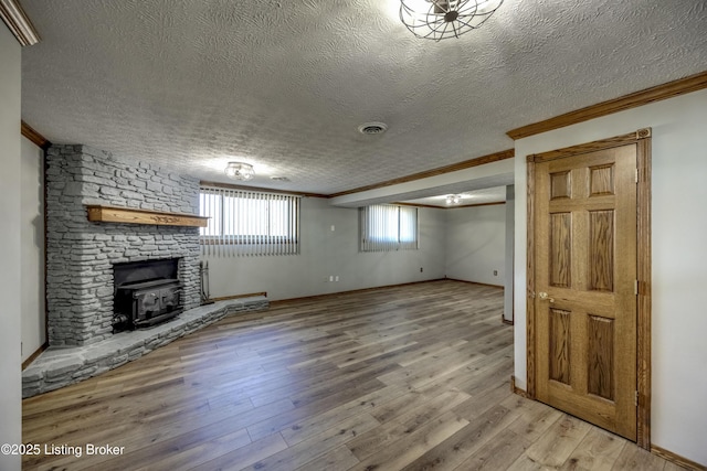 below grade area featuring baseboards, visible vents, a textured ceiling, crown molding, and light wood-style floors