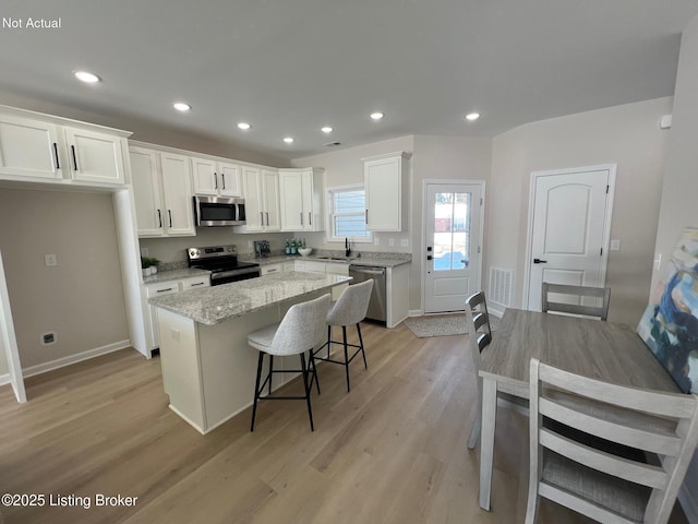 kitchen featuring a kitchen island, visible vents, white cabinetry, light wood-style floors, and appliances with stainless steel finishes