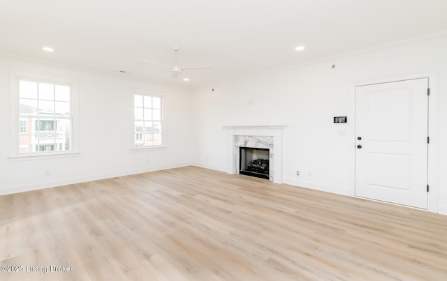 unfurnished living room with light wood finished floors, recessed lighting, a high end fireplace, and baseboards