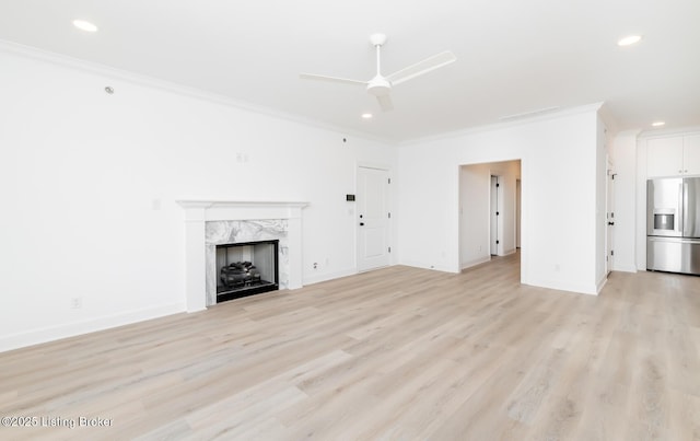 unfurnished living room with light wood-style floors, a fireplace, and crown molding