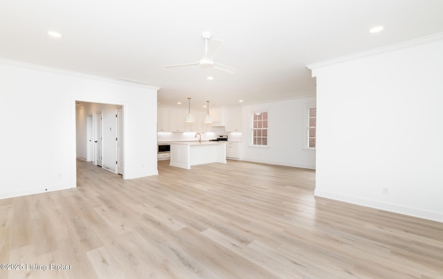 unfurnished living room featuring ornamental molding, a ceiling fan, and light wood-style floors