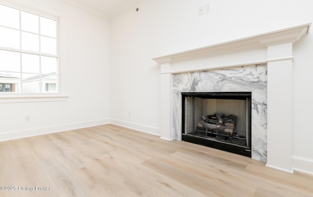 unfurnished living room with a fireplace, baseboards, and wood finished floors