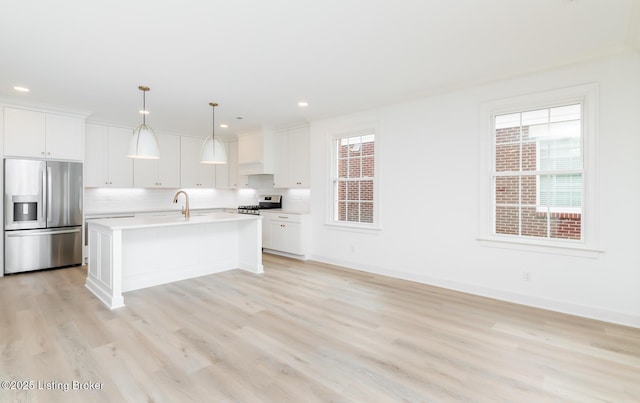 kitchen with a sink, white cabinetry, light wood-style floors, light countertops, and appliances with stainless steel finishes