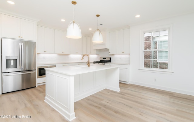 kitchen featuring decorative backsplash, appliances with stainless steel finishes, light countertops, light wood-type flooring, and a sink