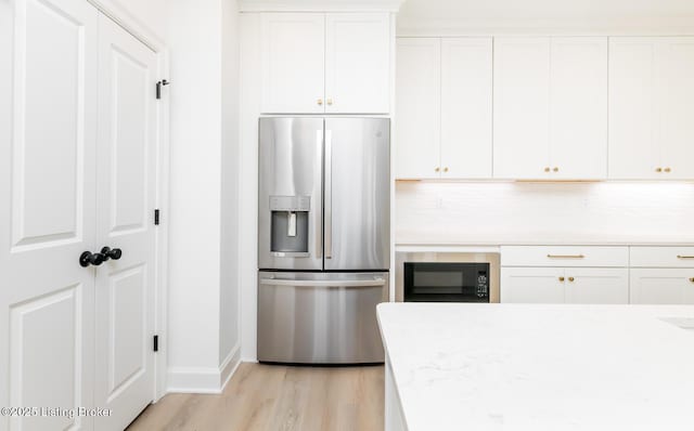 kitchen featuring white cabinets, built in microwave, light countertops, and stainless steel fridge with ice dispenser