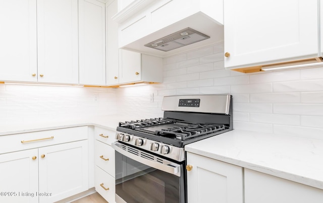 kitchen featuring white cabinets, stainless steel gas range, custom exhaust hood, light stone countertops, and tasteful backsplash