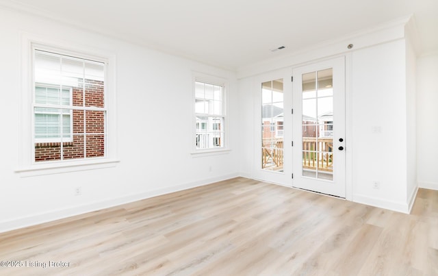 spare room with light wood-type flooring, visible vents, and baseboards