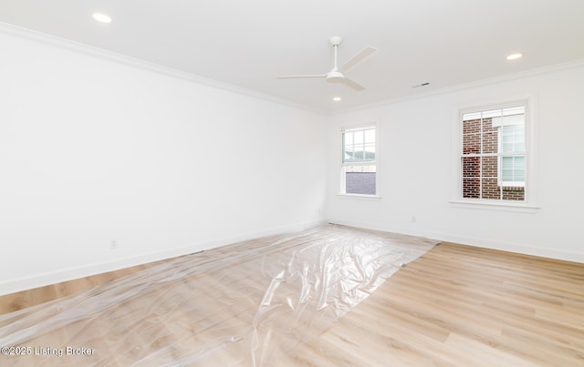 empty room featuring crown molding, baseboards, and wood finished floors