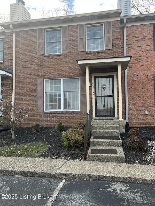 property entrance with brick siding and a chimney