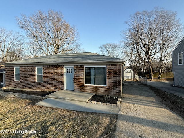 view of front facade with a storage unit, an outdoor structure, and brick siding