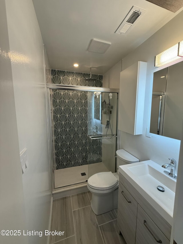 bathroom with toilet, a stall shower, visible vents, and vanity