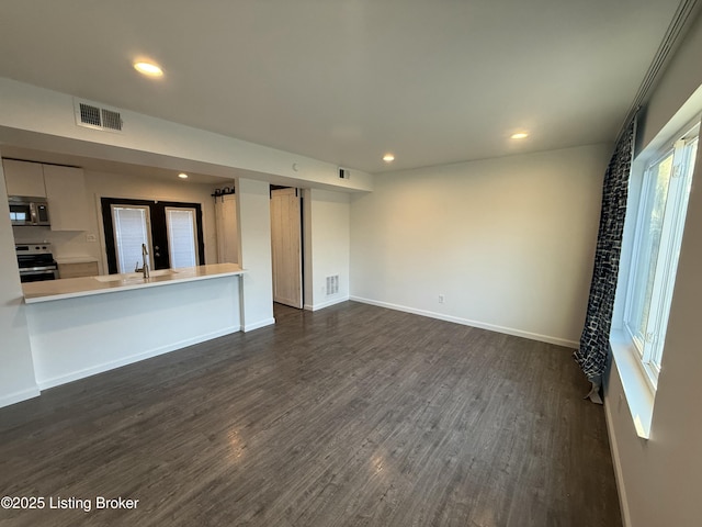 unfurnished living room featuring baseboards, visible vents, dark wood-style flooring, and recessed lighting