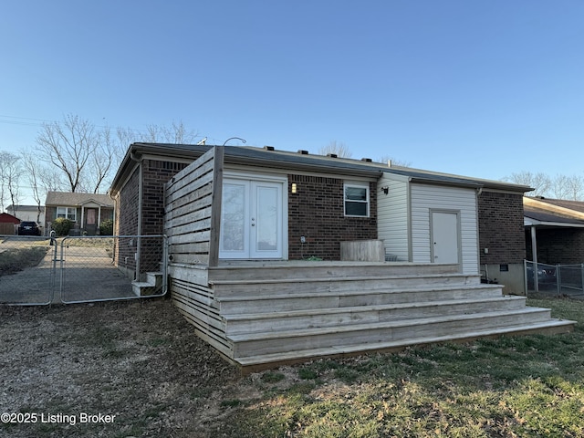 rear view of house with brick siding, fence, and a gate