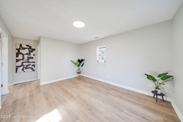 unfurnished room featuring light wood-type flooring, visible vents, and baseboards