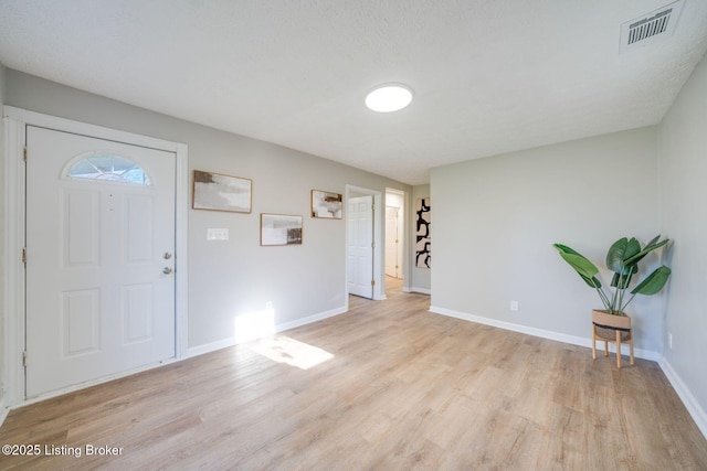 foyer entrance featuring light wood-style flooring, visible vents, and baseboards